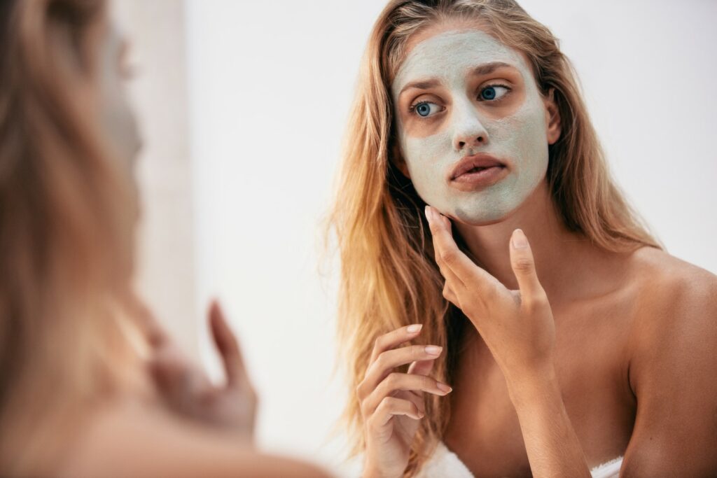 Woman,Looking,In,The,Mirror,With,Mask,On,Her,Face.