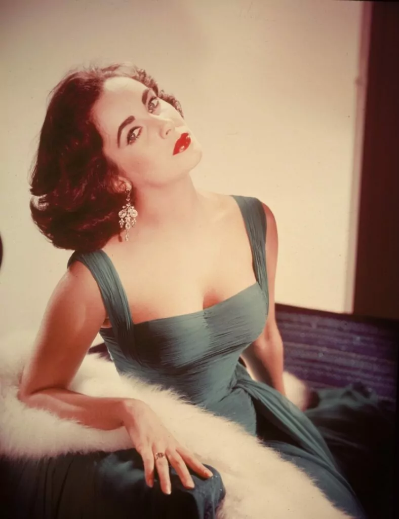 Portrait of British-born actor Elizabeth Taylor in a form-fitting green dress as she sits with her head tilted back exposing her neck, circa 1950s. (Photo by Hulton Archive/Getty Images)