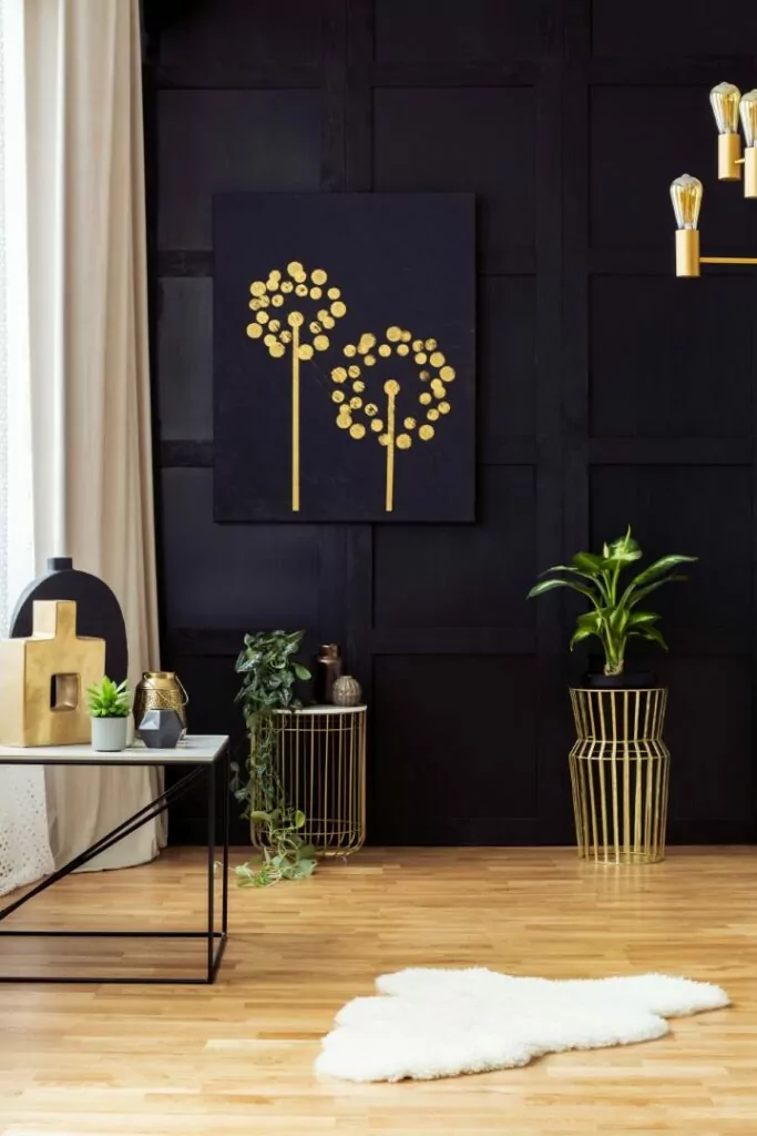 Elegant living room interior with golden accents, painting on a black wall, plants and fur rug. Real photo