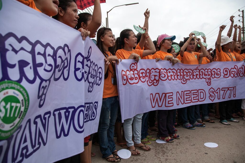 PHNOM PENH, CAMBODIA - SEPTEMBER 17: A group of garment workers demonstrate inside the Canadia Industrial Park during a protest demanding an increase of their minimum salary on September 17, 2014 in Phnom Penh, Cambodia. Thousands of garment factory workers from across Cambodia are taking part in a global day of worker solidarity. Eight of Cambodia's workers unions who are organizing today's events are handing out stickers and t-shirts bearing 
