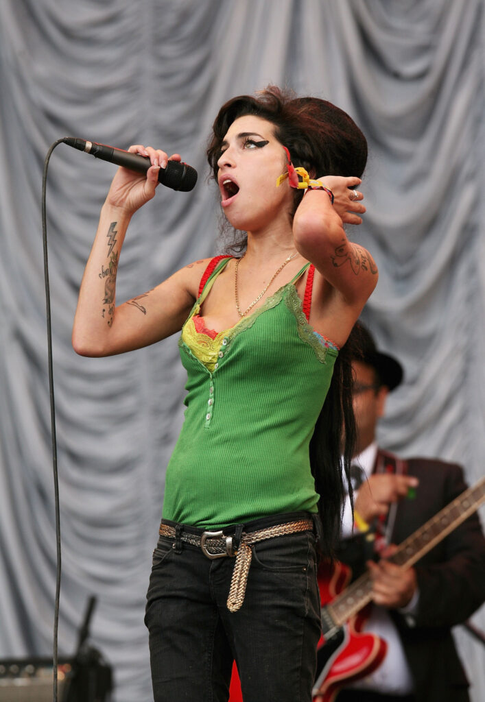 GLASTONBURY, UNITED KINGDOM - JUNE 22: Amy Winehouse performs on the Pyramid Stage on the first day ot the Glastonbury Festival at Worthy Farm, Pilton near Glastonbury, on June 22 2007 in Somerset, England. The Festival, that was started by dairy farmer Michael Eavis in 1970, has grown into the largest music festival in Europe. This year's Festival is the biggest yet and will have headline acts including The Who, The Artic Monkeys, Killers and Muse. (Photo by Rosie Greenway/Getty Images)