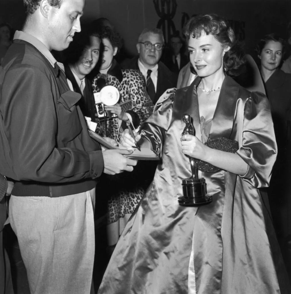 American actor Donna Reed (1921 - 1986) signs an autograph while holding her Oscar trophy at the Academy Awards, Los Angeles, California, March 25, 1954. (Photo by Hulton Archive/Getty Images)
