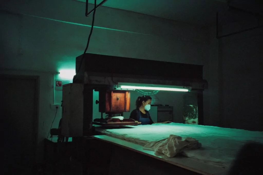 Radnica upravlja strojem za prešanje tkanina u tvornici u Kini Foto Carl Nenzen Loven Unsplash