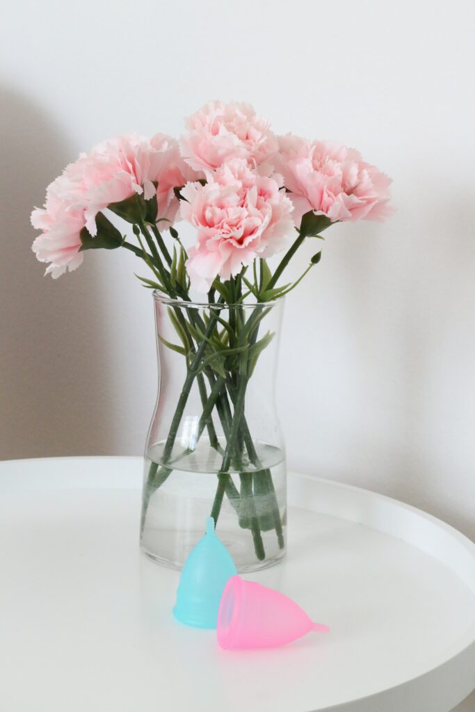dvije menstrualne casice na stolu uz cvijece