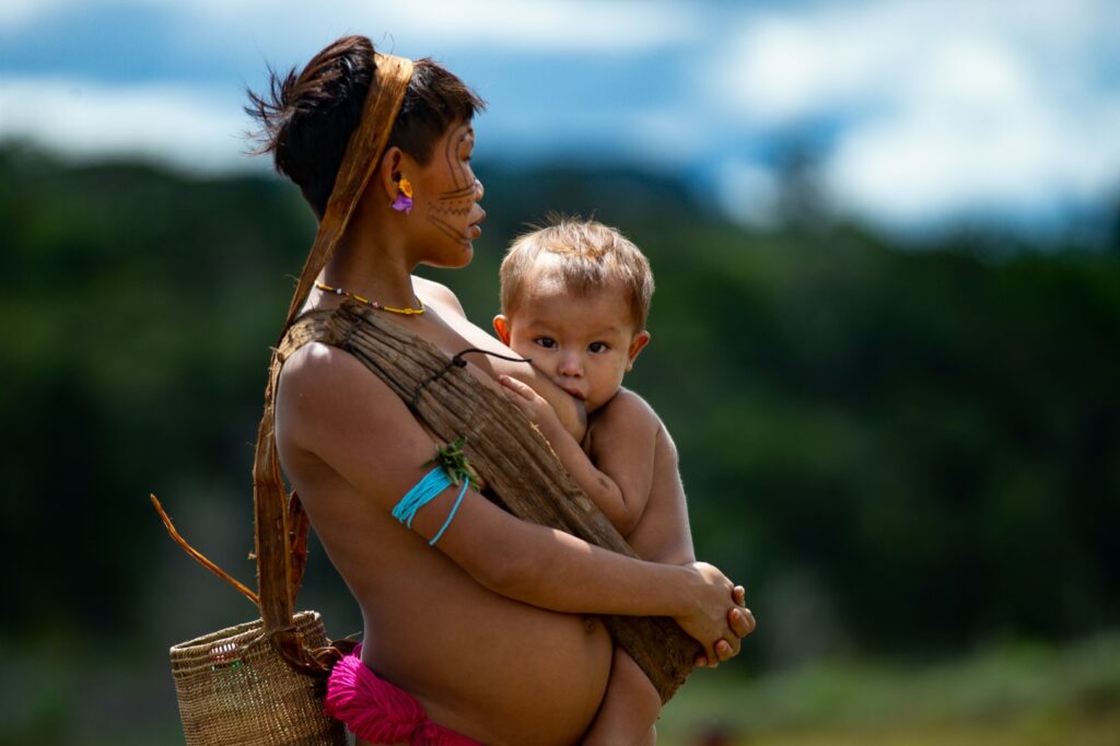 RORAIMA, BRAZIL - JULY 01: (EDITORS NOTE: image contains nudity) A Yanomami indigenous breastfeeds her infant as arriving to receive health care during the Yanomami / Raposa Serra do Sol Mission amidst at the coronavirus (COVID-19) pandemic at the 4 Special Border Platoon in the city of Alto Alegre on July 01, 2020 in Roraima, Brazil. The mission involves several ministries and seeks to intensify indigenous health care and Covid-19 prevention. Brazil has over 1,402,000 confirmed positive of Coronavirus cases, with 147 among Yanomamis, and 59,594 deaths across the country and 4 among Yanomamis. (Photo by Andressa Anholete / Getty Images)